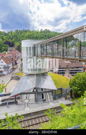 Moderno ponte pedonale su una stazione ferroviaria in una piccola città verde sotto un cielo blu, ampliamento Zob con costruzione di ponti per il nuovo Herman HES Foto Stock