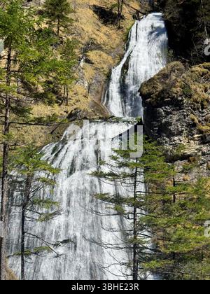 Tra le montagne alpine scorre un flusso d'acqua sotto forma di piccola cascata Foto Stock