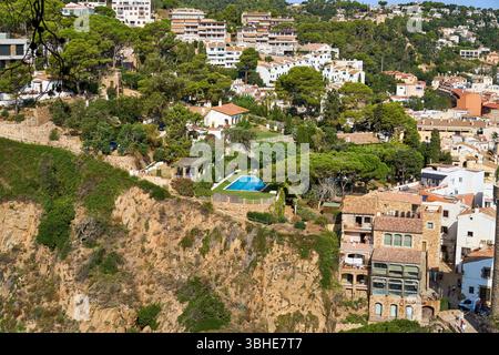 Una splendida vista di Tossa de Mar, che mostra edifici costieri annidati tra lussureggiante vegetazione e una piscina. Foto Stock