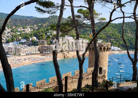 Vista panoramica di Tossa de Mar, con il Mar Mediterraneo, una torre di pietra, alberi e una pittoresca spiaggia con barche. Foto Stock