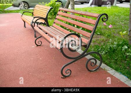 Bellissime panchine decorative in legno in un parco cittadino. Moderne panche vuote in legno. Messa a fuoco selettiva. Foto Stock