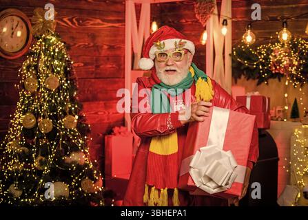 dono nelle sue mani. Regali all'albero di Natale. buon natale. regali da babbo natale. l'uomo barbuto va a fare shopping. regali di natale. felice anno nuovo. babbo Natale segreto Foto Stock