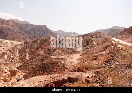 Un paesaggio desertico con montagne sullo sfondo. Il cielo è limpido e il sole splende Foto Stock