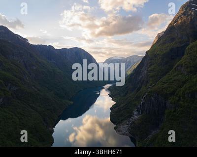Paesaggio aereo mozzafiato della Norvegia. Vista di un drone su un pittoresco fiordo incastonato tra verdi montagne nei raggi dorati del sole che tramonta. Foto Stock