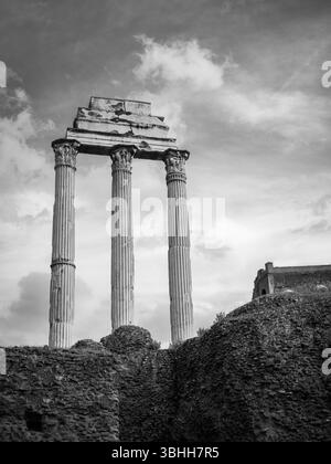 Tre colonne sopravvissute del Tempio di Castore e Polluce si stagliano come resti iconici nel foro Romano, catturati con fotografie in bianco e nero. Foto Stock