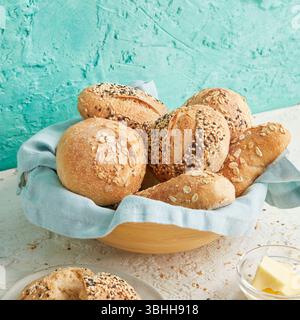 Panini per la colazione in una ciotola di legno con burro sul lato: Un ambiente rustico per la colazione perfetto per mangiare in modo pulito, preparare cibi e pasti mattutini Foto Stock