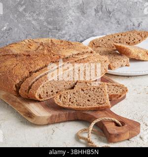 Pane intero di farro su tavola di legno: Un pane artigianale rustico e ricco di fibre, perfetto per mangiare pulito, fare colazione o per una sana fotografia in stile panetteria Foto Stock