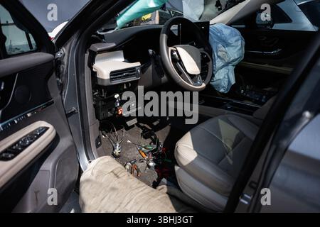 Abitacolo del veicolo con airbag visibili, cruscotto smontato e componenti elettronici esposti. Foto Stock
