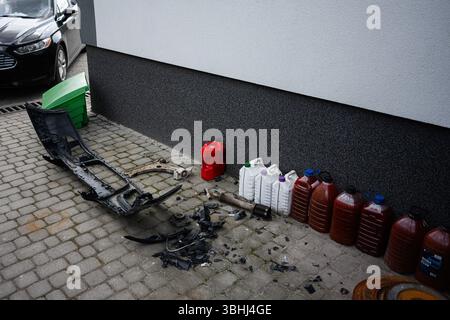 Varie parti di automobili e contenitori in plastica su un marciapiede vicino a un muro di un edificio. Foto Stock