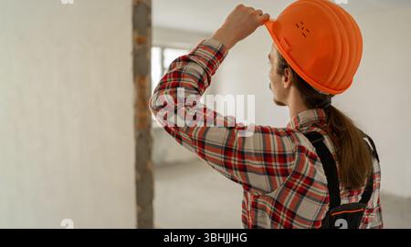 Vista posteriore del costruttore per l'impresa edile in un edificio non finito. Operaio edile Foto Stock