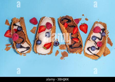 Vari gelati taco dolci. Conchiglie di taco con cioccolato e gelato alla vaniglia con frutta, frutti di bosco e condimenti diversi Foto Stock