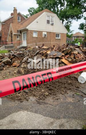 Detroit, Michigan - i segnali segnalano il pericolo di amianto in cui una casa è stata demolita. La casa era stata pesantemente danneggiata da un incendio un anno prima ed era una ne Foto Stock
