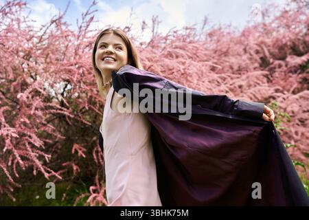 Una donna sorridente in abito gode di una calda giornata floreale. Foto Stock