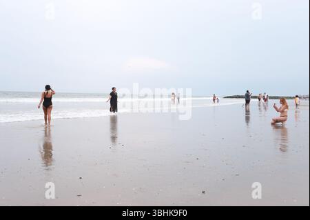 Serata alla spiaggia di Rockaways, Queens, New York. Persone che passeggiano per la spiaggia e si divertono a modo loro. Amici che scattano foto e posano. Foto Stock