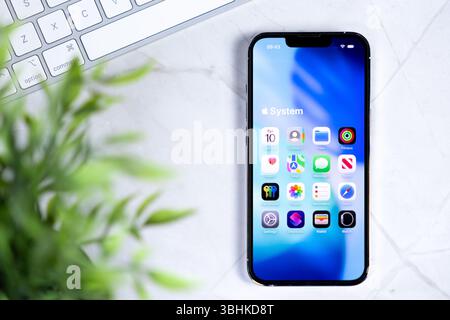 Poznan, Polonia - 10 giugno 2025: Smartphone che visualizza il nuovo iOS 26, vetro liquido nel design, sfondo blu brillante, testo di sistema e icone delle app Foto Stock