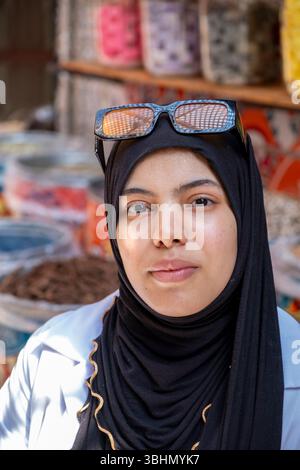 Una giovane donna che vende spezie in una stalla al mercato di Medina. Casablanca, Marocco. Foto Stock