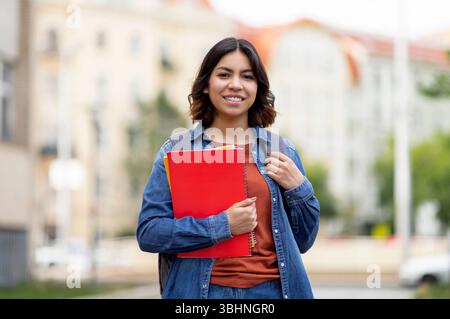 Ritratto all'aperto di una studentessa araba sorridente con zaino e libri degli esercizi Foto Stock