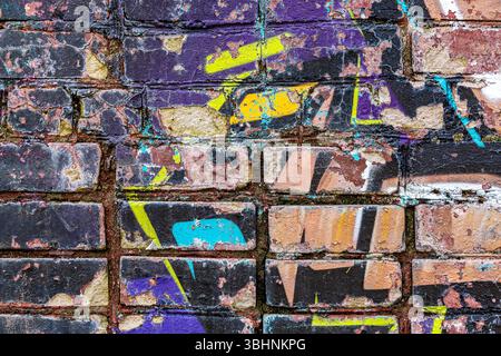 street art danneggiata su pareti in mattoni intemprati. sfondo astratto di graffiti urbani. Foto Stock