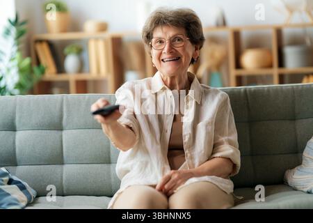 Donna anziana che guarda la TV, i film. Pensionati che passano del tempo a casa. Foto Stock