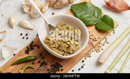 Pasta di curry verde tailandese. A base di erbe fresche, peperoncini, aglio e citronella, serviti in una ciotola rustica. Perfetto per una cottura veloce e piatti caldi. Foto Stock