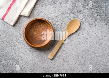 Recipiente in legno e cucchiaio sulla superficie del piano di lavoro della cucina grigio testurizzato Foto Stock