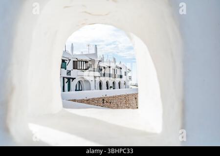 L'iconica architettura bianca del villaggio di Binibeca Vell è visibile attraverso un'arcata. Città costiera di Menorca, case bianche, Isole Baleari Foto Stock