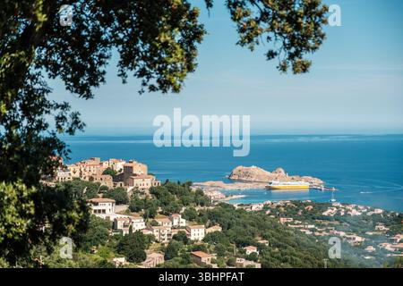 Ile Rousse, Corsica, Francia - 25 maggio 2025: Un traghetto Corsica Ferries si trova nel porto di Ile Rousse sull'isola mediterranea della Corsica con il Foto Stock