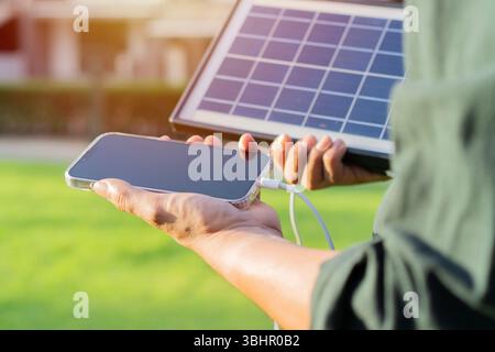 Il tizio sta portando un telefono cellulare e sta caricando con il solare portatile in mano. Energia ecologica per attività ricreative all'aperto. Messa a fuoco selettiva. Foto Stock