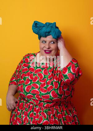 Una donna di taglia superiore sorridente e toccante con la testa in un abito a cocomero Foto Stock