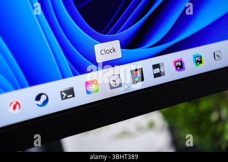 Poznan, Polonia - 6 giugno 2025: Primo piano di un display del computer che mostra la barra delle applicazioni con un puntatore del mouse che attiva l'app Clock, sottolineando il so moderno Foto Stock