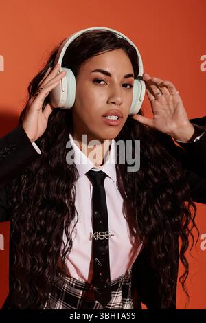 Una giovane donna dai capelli lunghi e bellissimi ama le sue canzoni preferite mentre è circondata da colori caldi. Foto Stock
