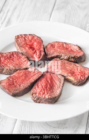 Tenera bistecca di mignon in filetto, perfettamente cotta, tagliata a fette ed elegantemente presentata su un piatto Foto Stock