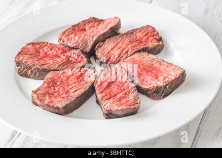 Tenera bistecca di mignon in filetto, perfettamente cotta, tagliata a fette ed elegantemente presentata su un piatto Foto Stock