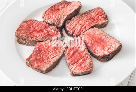 Tenera bistecca di mignon in filetto, perfettamente cotta, tagliata a fette ed elegantemente presentata su un piatto Foto Stock