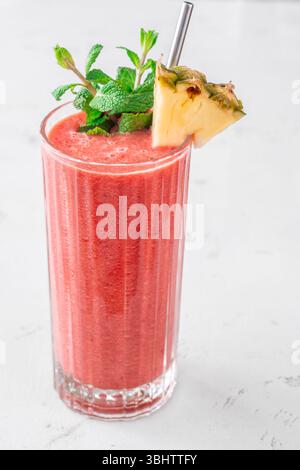 Frullato tropicale cremoso con ciliegia, banana e ananas, guarnito con menta e ananas Foto Stock