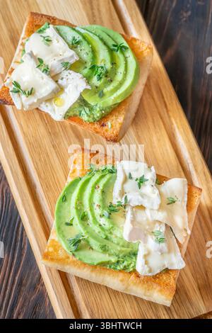 Panini tostati con ciabatta a strati di brie, avocado e spinaci cremosi, erbe aromatiche delicate Foto Stock