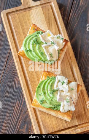 Panini tostati con ciabatta a strati di brie, avocado e spinaci cremosi, erbe aromatiche delicate Foto Stock