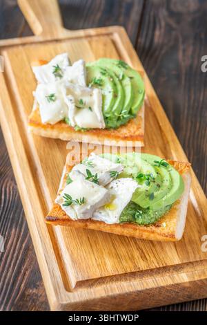 Panini tostati con ciabatta a strati di brie, avocado e spinaci cremosi, erbe aromatiche delicate Foto Stock