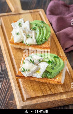 Panini tostati con ciabatta a strati di brie, avocado e spinaci cremosi, erbe aromatiche delicate Foto Stock
