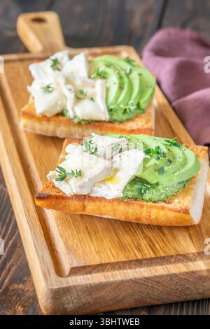 Panini tostati con ciabatta a strati di brie, avocado e spinaci cremosi, erbe aromatiche delicate Foto Stock