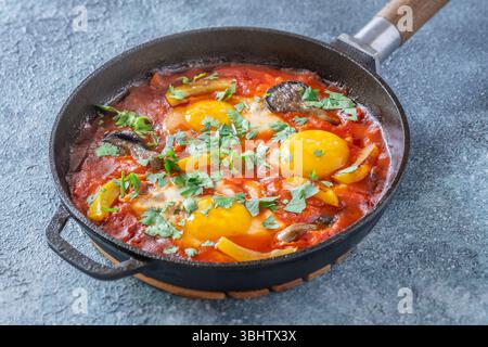 Uova sospese a base di pomodoro speziato con funghi, peperoni ed erbe fresche Foto Stock