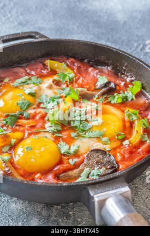 Uova sospese a base di pomodoro speziato con funghi, peperoni ed erbe fresche Foto Stock