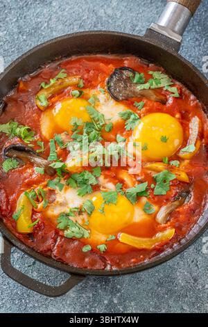Uova sospese a base di pomodoro speziato con funghi, peperoni ed erbe fresche Foto Stock