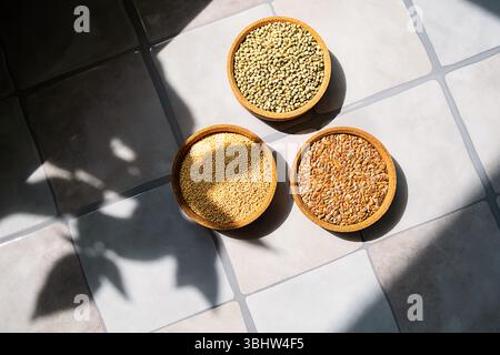 Tre ciotole con semi di Amaranto, lino e canapa su una superficie piastrellata con luce solare. Cibo sano e nutriente. Foto Stock