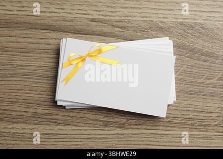Carta regalo vuota con arco giallo su un tavolo in legno, vista dall'alto. Mockup per il design Foto Stock
