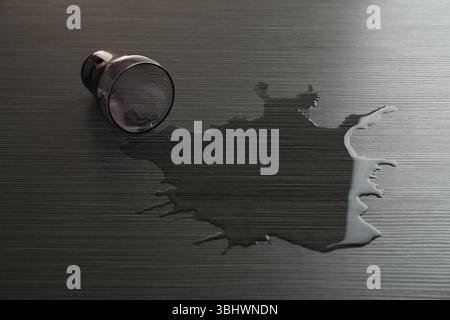 Vetro rovesciato e acqua versata su un tavolo di legno Foto Stock