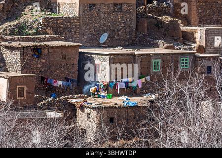 Una tipica casa locale su una collina con vestiti su una linea di lavaggio in un villaggio berbero, il Parco Nazionale di Toubkal, le montagne dell'Atlante, il Marocco, il Nord Africa Foto Stock