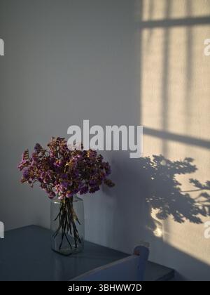 Luce soffusa del tramonto su mobili blu-grigio e decorazioni floreali. Foto Stock