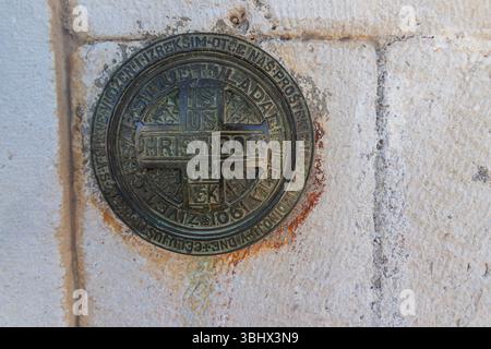 Šolta, CROAZIA, 08.21.2020: Foto ravvicinata di una placca religiosa dal design complesso con iscrizioni incastonate su un muro di pietra, che evoca un e sacro Foto Stock