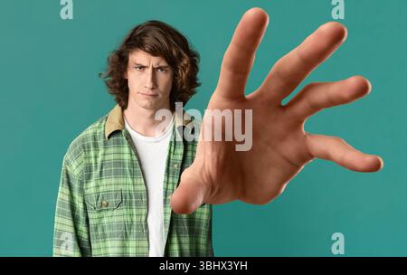 Ragazzo giovane che afferra qualcosa su sfondo turchese Foto Stock